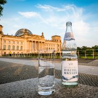 Mineralwasserflasche und gefülltest Glas auf Gehweg vor dem Reichstagsgebäude